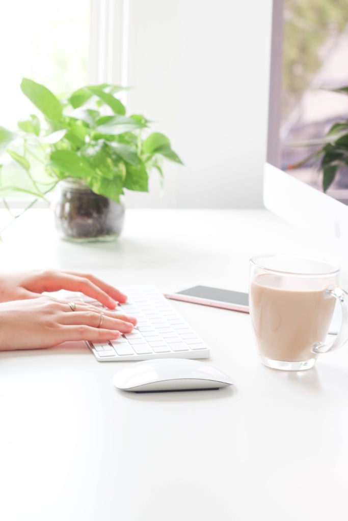 graphic of woman's hands typing. coffee and plant decorate the screen